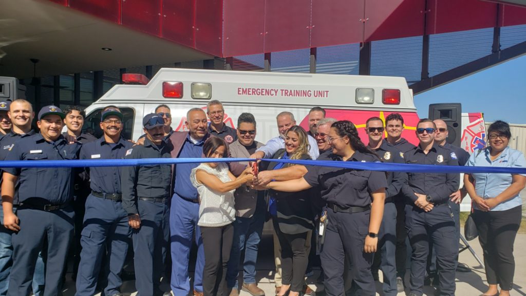 EMTs, paramedics, Otay Mesa and college leadership cut ribbon in front of new ambulance donation.