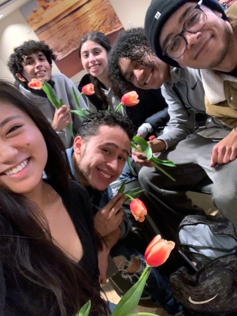 Students smiling into the camera, with flowers in hand.  