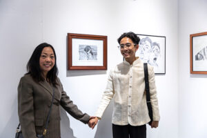 SWC student, Ivan Medida holding hands with his mom in front of his art piece depicting her comforting him.